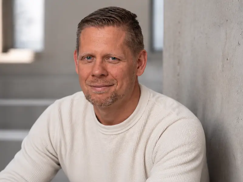 Steffen Knippertz, Ausbilder und Referent für ADQ®, im hellen Pullover vor einer Betontreppe